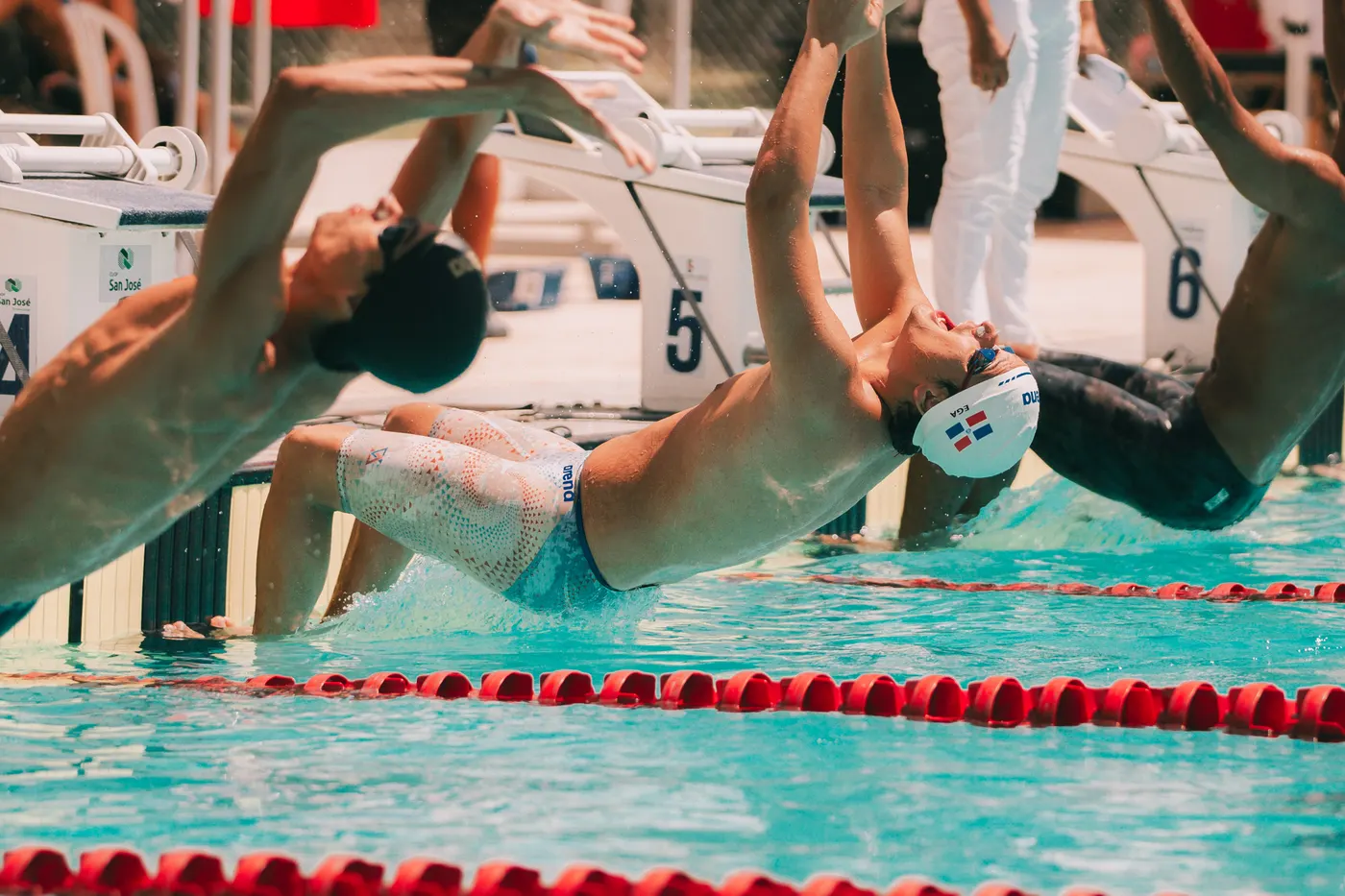 Salida de espalda: nadadores agarrados al borde de la piscina antes de la señal.
